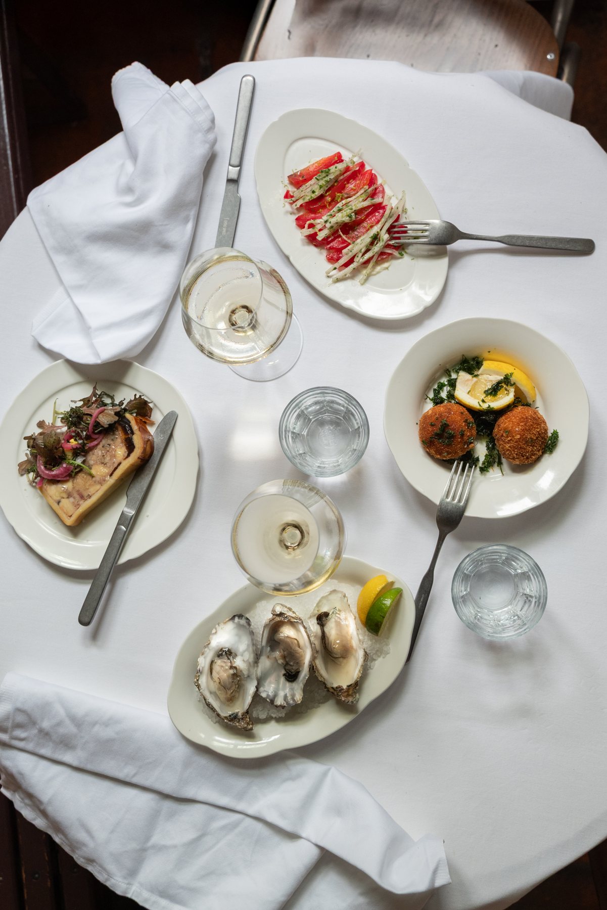 Oesters, kroketten en tomatensalade op een gedekte tafel
